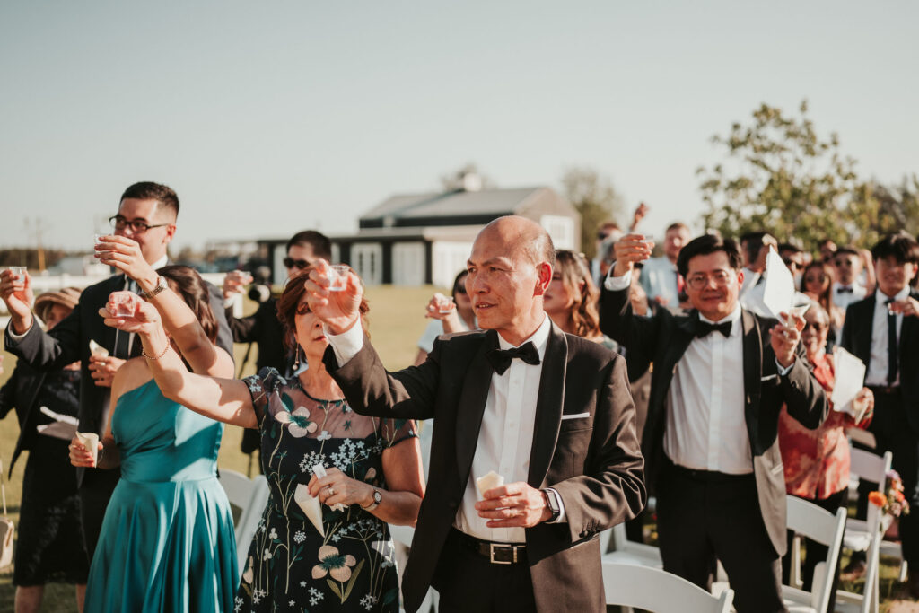 A wedding guest raising his shot glass