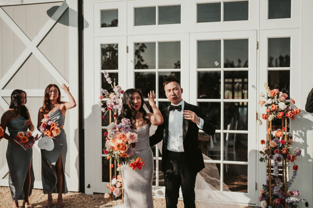 Bride and groom waving at their wedding guests