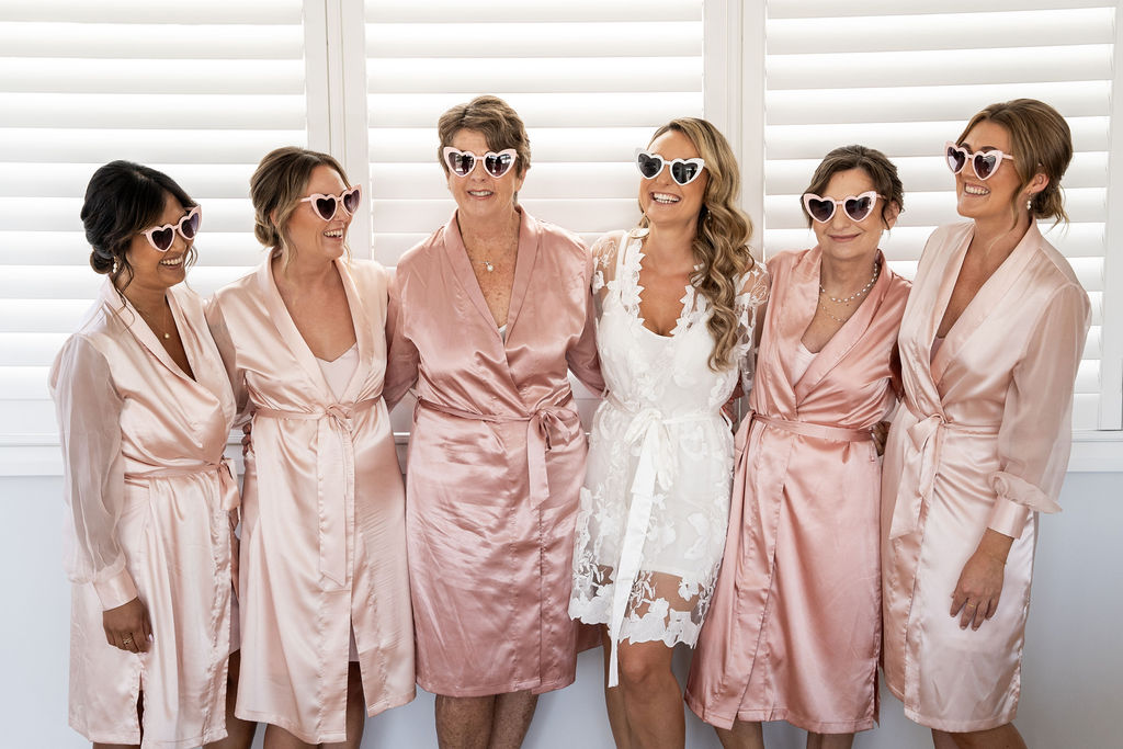 Bride and her bridal party in their pre-wedding outfit wearing heart sunglasses
