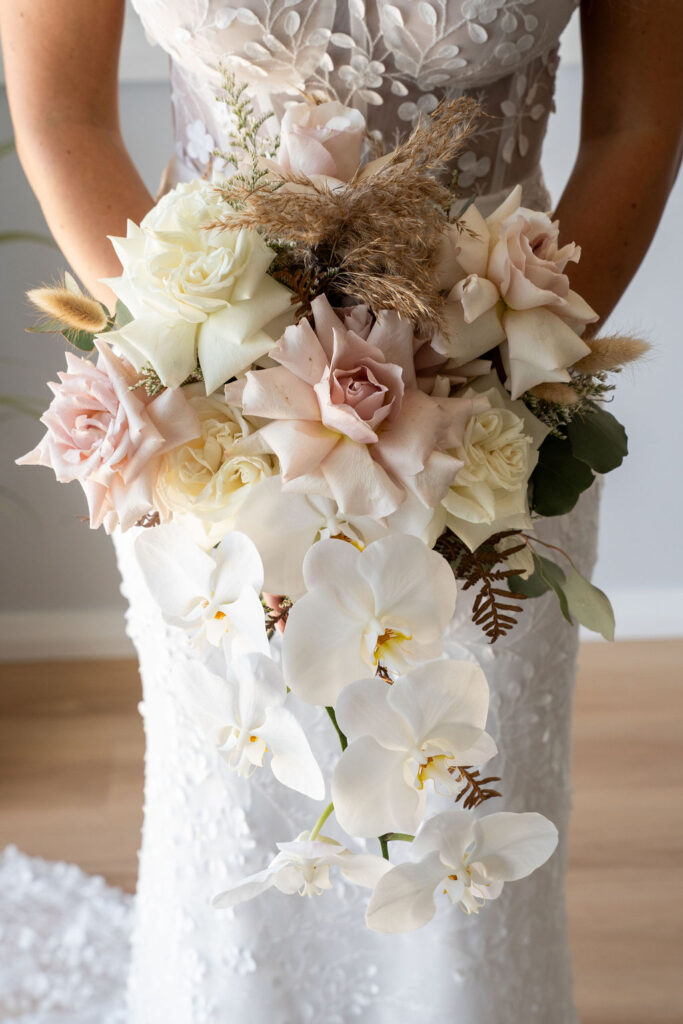 Front view of a pastel-coloured bouquet held at hip-height by the bride
