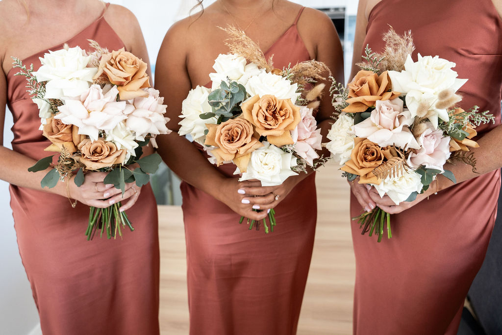Three bridesmaids with their white and orange bouquets