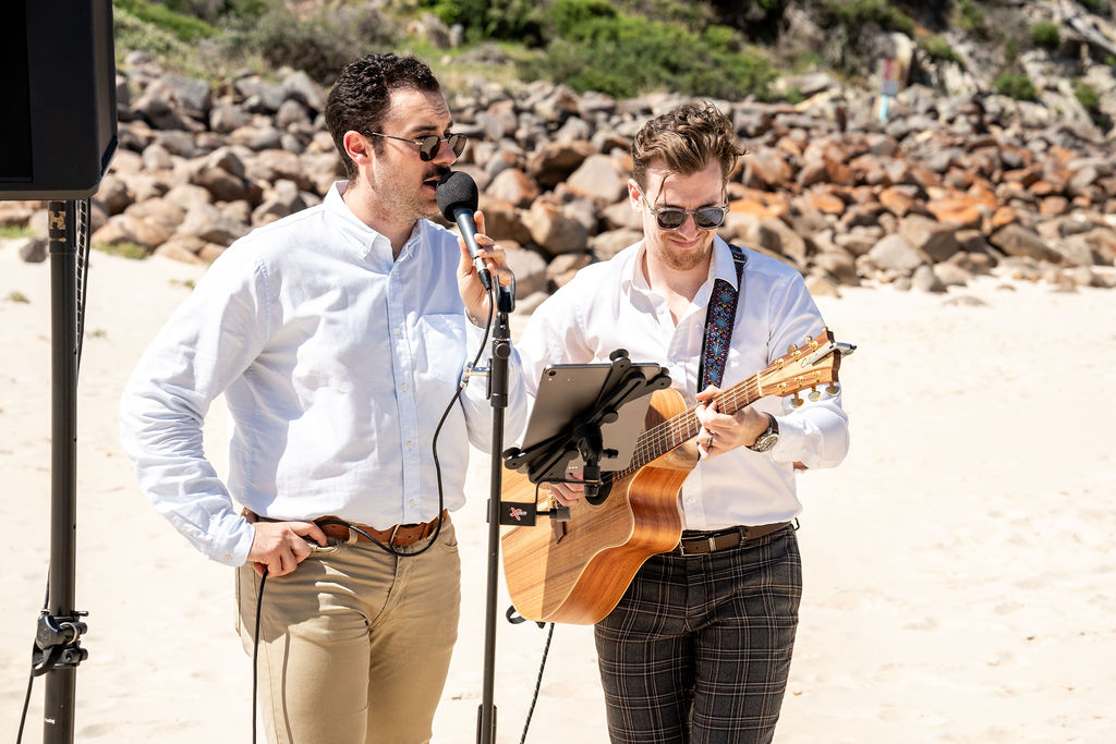 A wedding singer and guitarist singing for a wedding by the sea shore at Zenith Beach