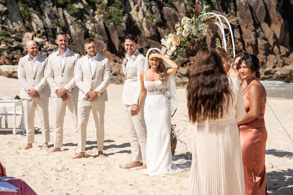 Celebrant Julie Muir mid-ceremony with the bride, groom, groomsmen and bridesmaids looking at her ont Zenith Beach