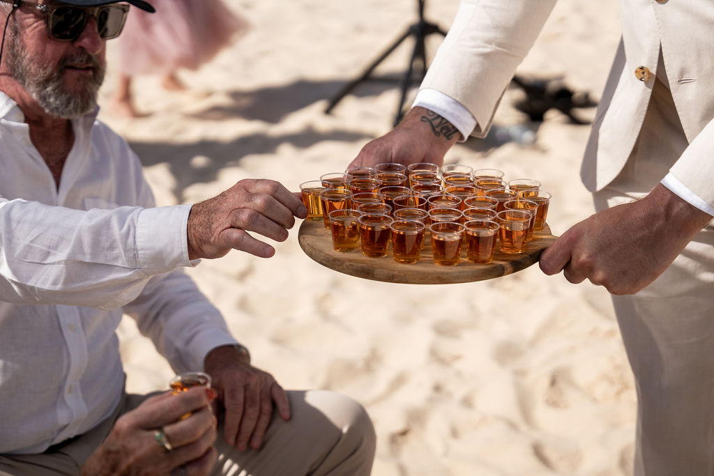 A groomsman serving shots of alcohol to the wedding guest at Zenith Beach