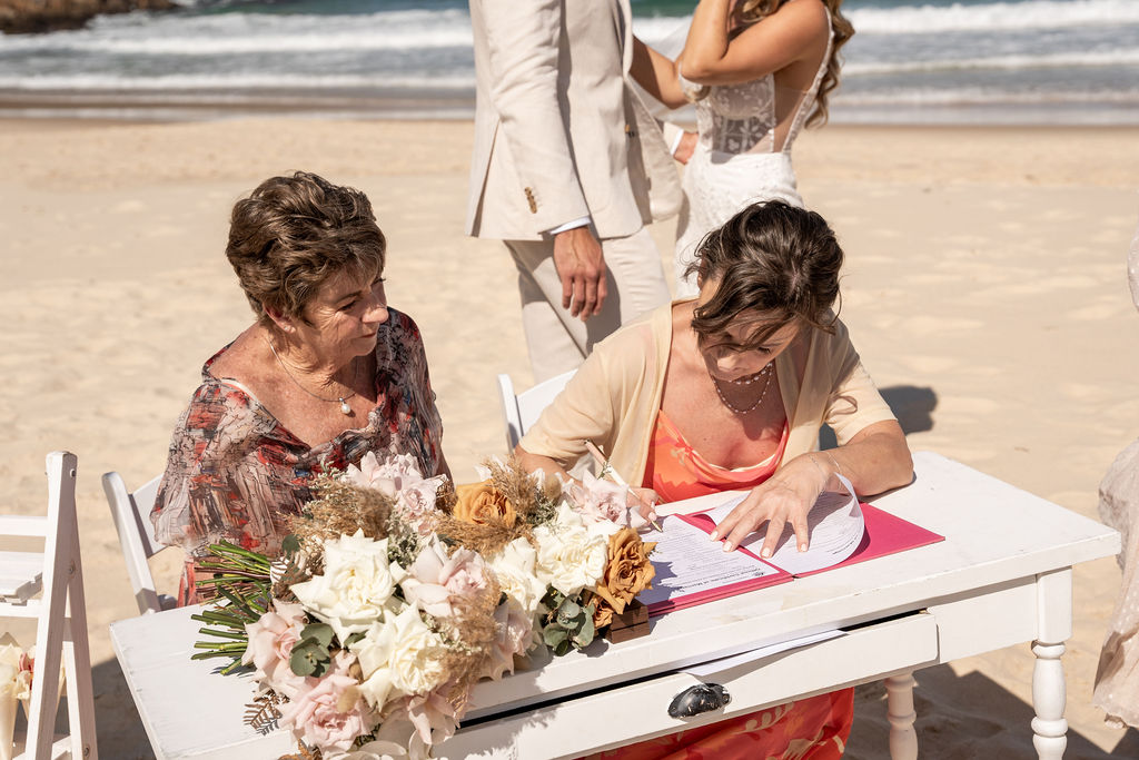 Wedding witnesses sitting at a table and signing the wedding certificate at Zenith Beach