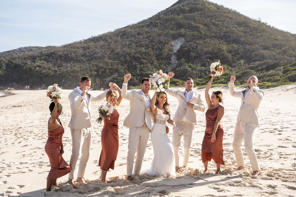 Bride and groom cheering with their bridal party at Zenith Beach