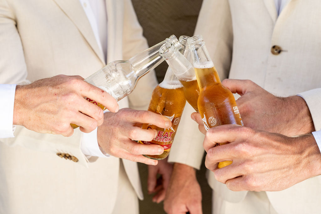 4 groomsmen clinking their bottles of beer