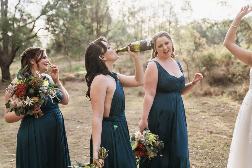 Bridesmaid knocking back champagne from the bottle at at Leaves and Fishes in Lovedale after a wedding ceremony