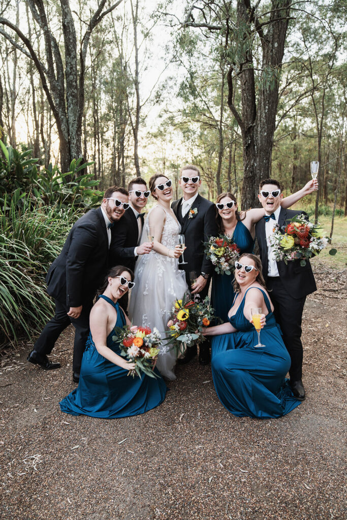 Bridal party posing for photos with heart sunglasses at Leaves and Fishes
