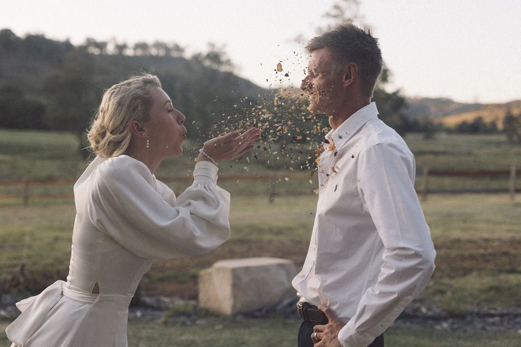 Bride blowing eco-confetti in husband's face at Wallaringa Farm