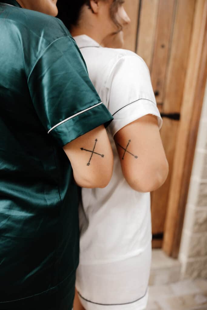 Bride and bridesmaid with matching cross tattoos. 