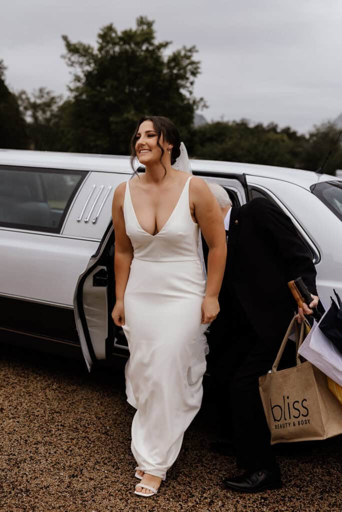 Bride in sleek dress gets out of car at Peterson House Chapel