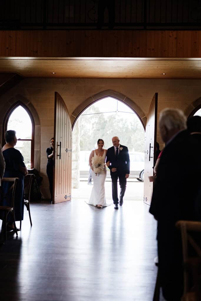 Bride walks in chapel doors with father at Peterson House Chapel