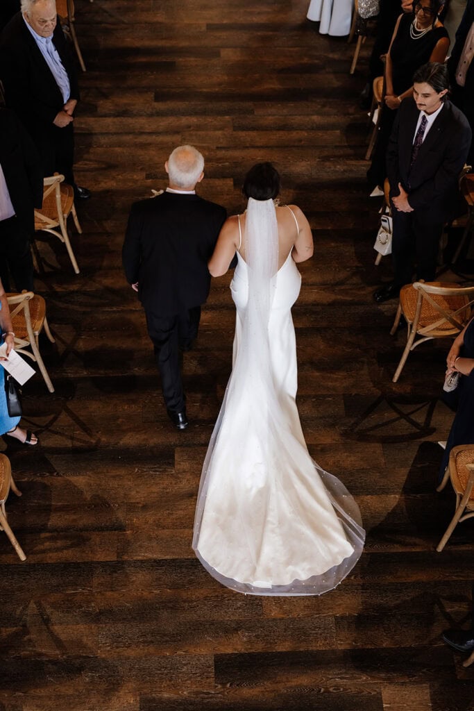 Bride walks down aisle at Peterson House Chapel. Photo taken from above on the chapel gallery level. 