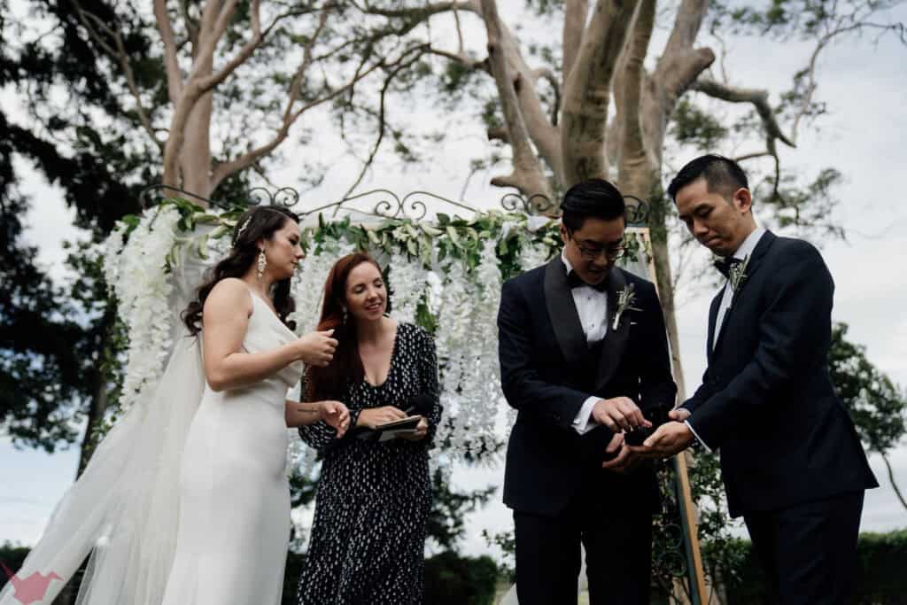 Celebrant Julie Muir stands with the couple as groomsman brings up the ring at Anambah House