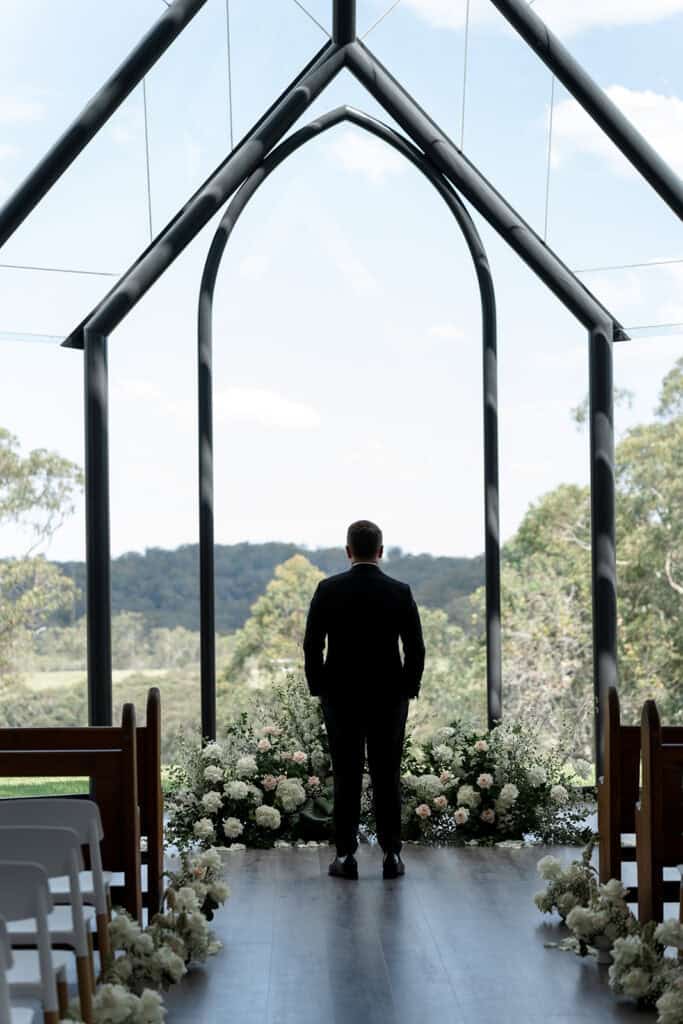 Groom staring out the window at Chapel Ridge contemplatively 