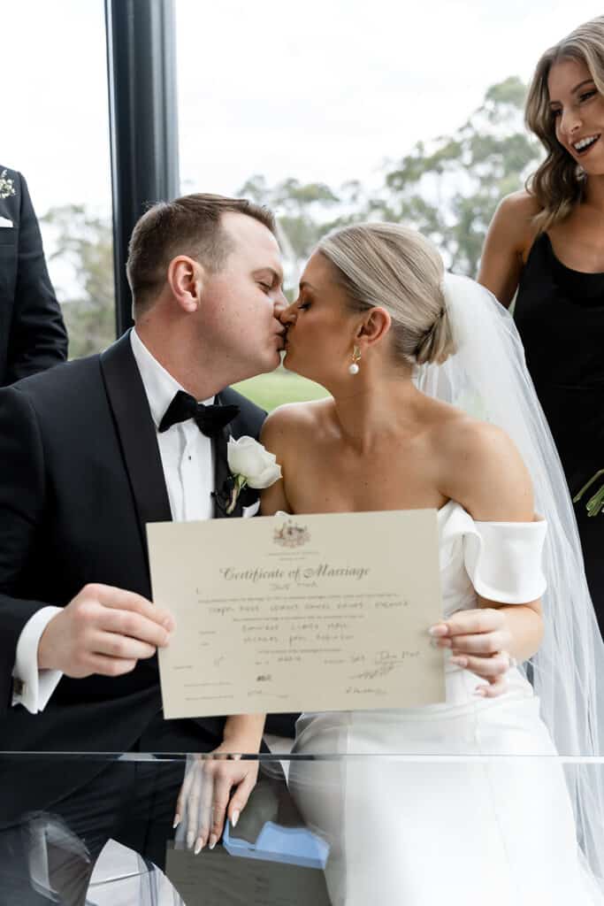 Chapel Ridge: couple holding marriage cert after signing while kissing