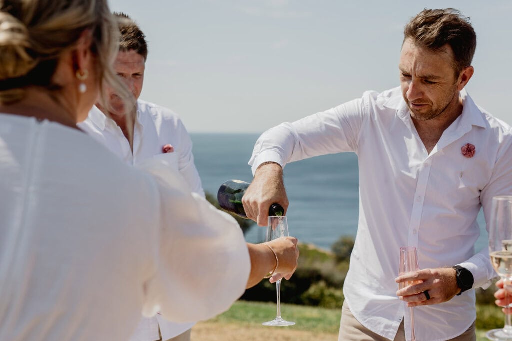 Groom pouring champagne for friends at  Newcastle coastal wedding