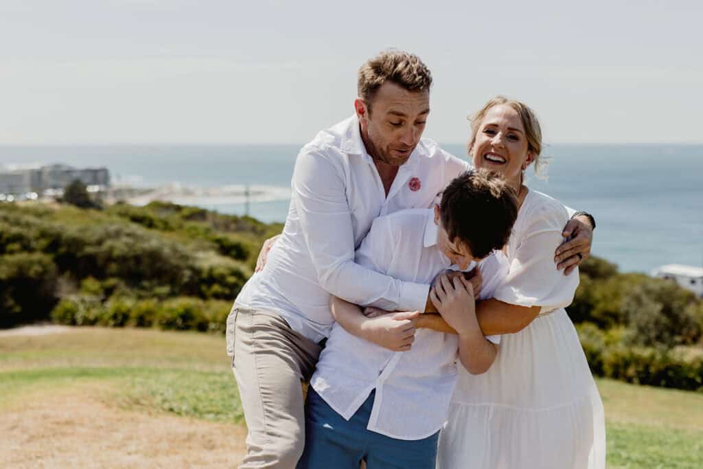 Family hugging each other enthusiastically at  Newcastle coastal wedding