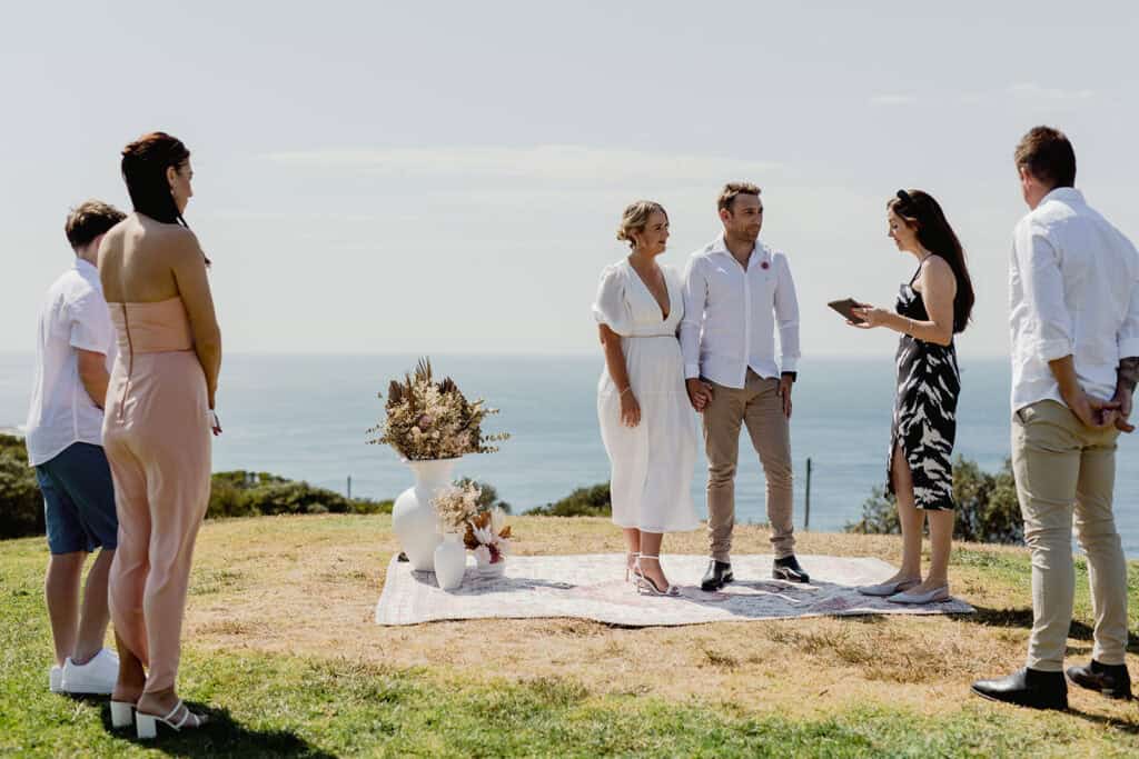 Couple standing on rug with dried flowers in vases with ocean view for  Newcastle coastal wedding