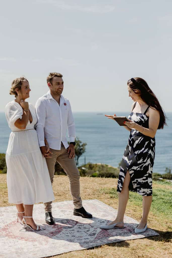 Coup[le standing on rug for their  Newcastle coastal wedding