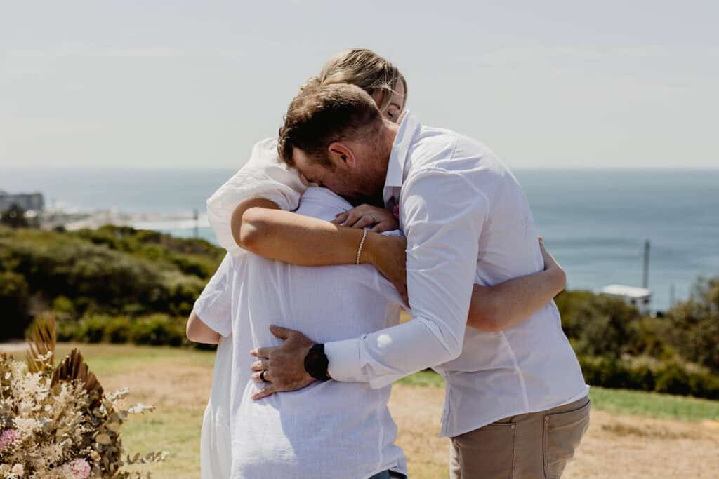 Tender group hug for family at  Newcastle coastal wedding