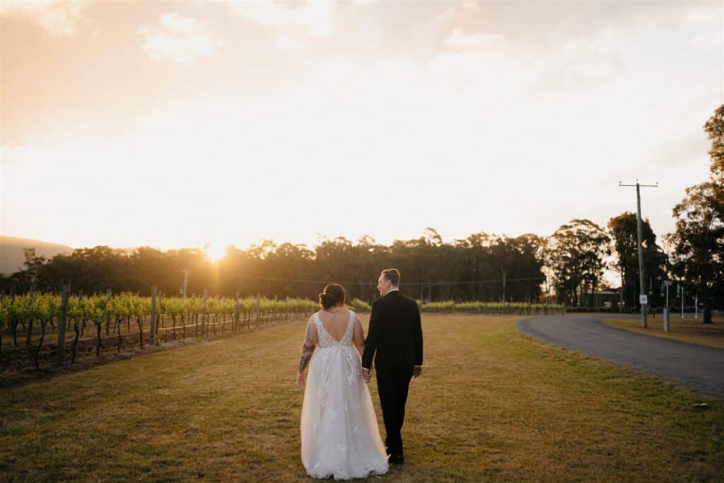 Newlyweds walking across the paddock at The Wine House