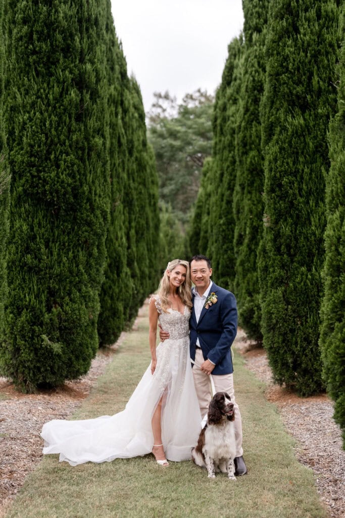 Newlyweds and dog on leash standing in gardens of Redleaf Wollombi