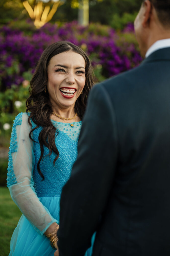 Bride smiles at groom in Jesmond Park wedding of Afghan couple