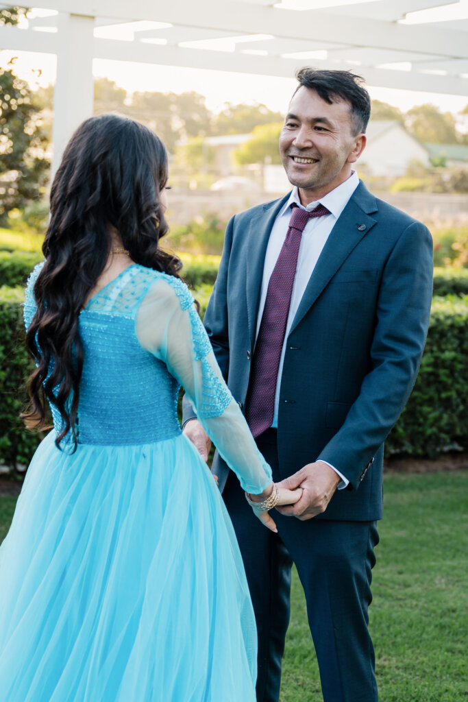 Groom smiles at bride in Jesmond Park wedding of Afghan couple