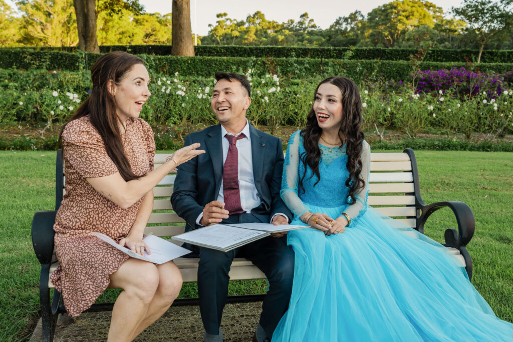 Celebrant ad couple sit on park bench to sign the legal paperwork for Jesmond Park wedding