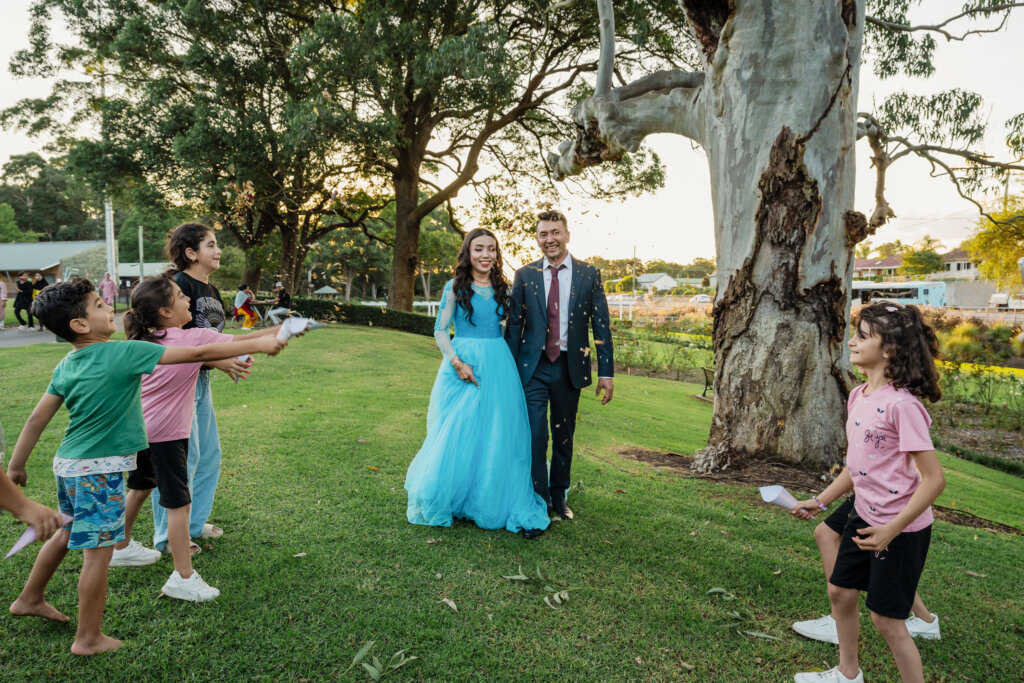 Local Afghan children throw rose petal confetti at Jesmond Park wedding