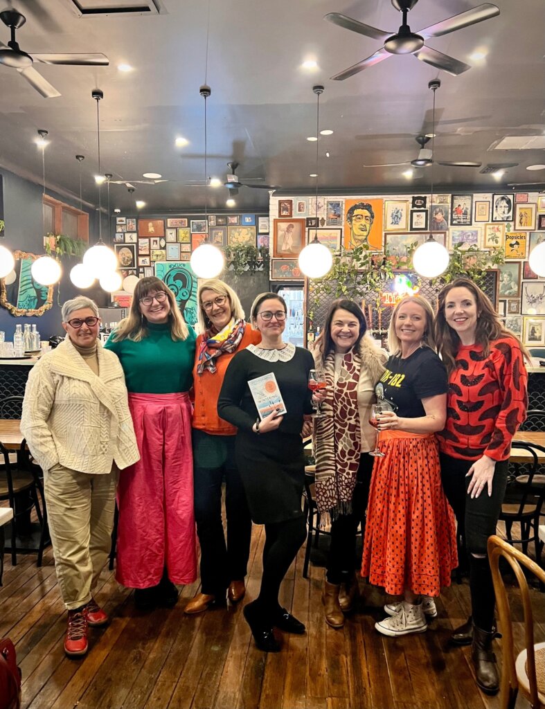 Book club attendees with a copy of Wintering by Katherine May